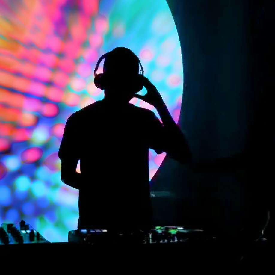 picture of DJ Lobito sitting on a sofa behind a cloud of smoke with two dogs